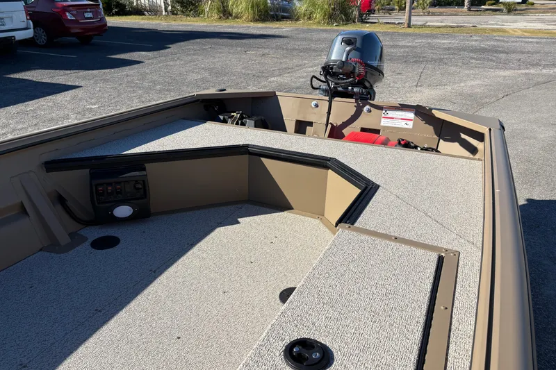 Slide: The Image of 2026 SeaArk DXS 1548 DKLD boat interior with motor, parked in a lot. - 10