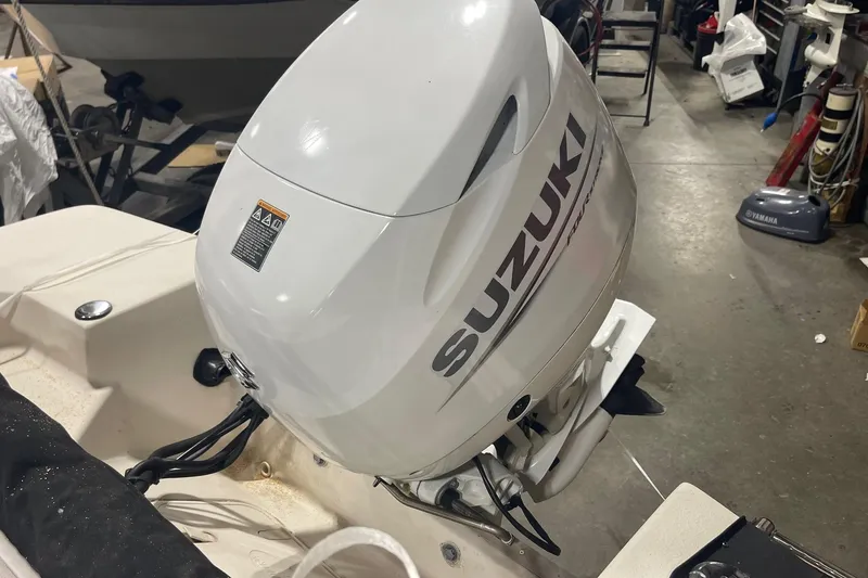 Slide: The Image of 2021 Carolina Skiff 162 JLS with Suzuki outboard motor in a workshop setting. - 6