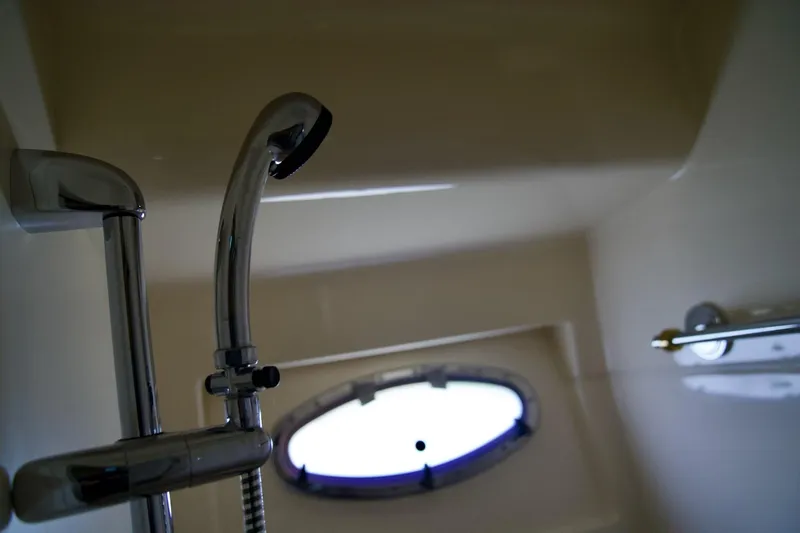Slide: The Image of Shower area inside a 2000 Carver 506 Motor Yacht, featuring chrome fixtures and a porthole window. - 51