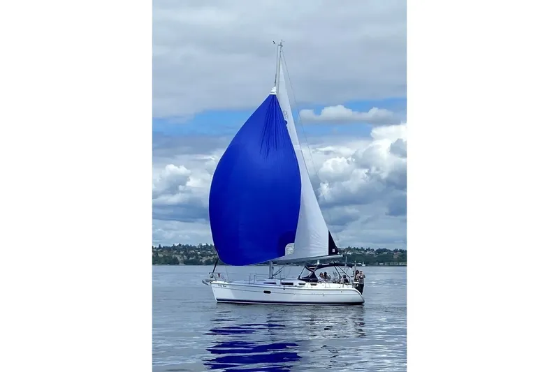 The Image of 2005 Hunter 36 sailboat with blue spinnaker on calm water under cloudy sky. - 0