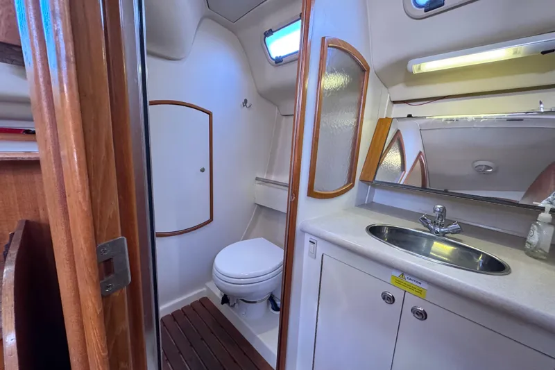 Slide: The Image of 2005 Hunter 36 yacht bathroom with toilet, sink, mirror, and wooden accents. - 16