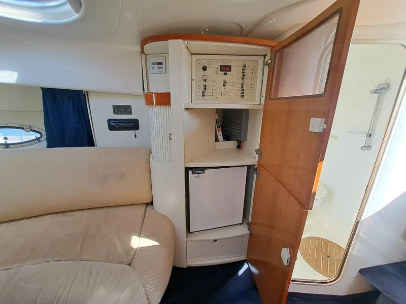 Slide: The Image of 2003 Cranchi Endurance 39 yacht interior with seating and table, docked near parked cars. - 16