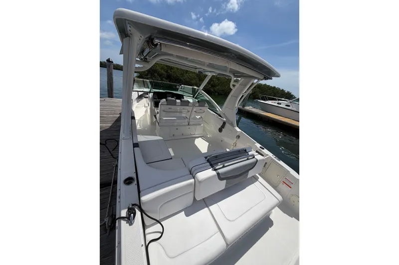 Slide: The Image of 2020 Chaparral 300 OSX boat interior with seating, docked by the water under a clear sky. - 12