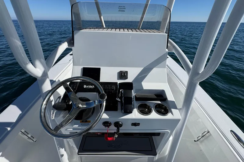 Slide: The Image of 2026 BlackJack 256 Coastal boat console with steering wheel, controls, and cup holders on open water. - 25