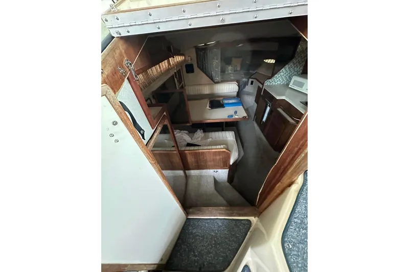 Slide: The Image of Interior of 1986 Sea-Ray 340 Express boat, featuring cozy seating and compact kitchen area. - 11