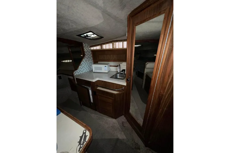 Slide: The Image of Interior of 1986 Sea-Ray 340 Express boat with kitchenette and wooden cabinetry. - 17