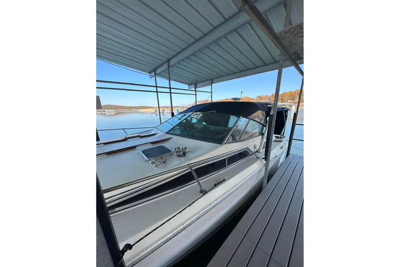 Slide: The Image of 1986 Sea-Ray 340 Express docked under a covered marina with scenic lake view. - 4