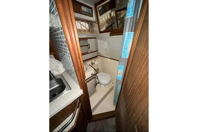 Slide: The Image of 1986 Sea-Ray 340 Express boat bathroom with sink, toilet, and shower curtain. - 7