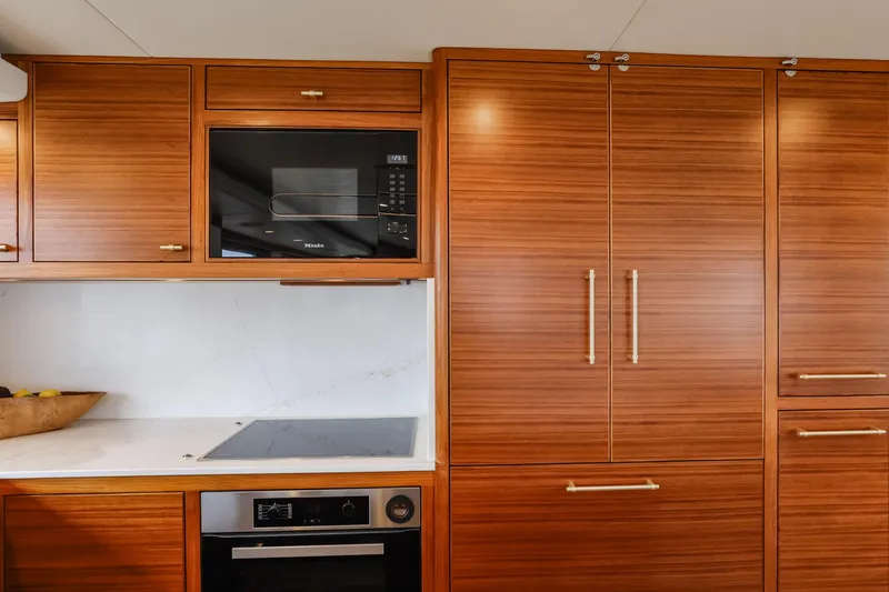 Slide: The Image of Luxurious kitchen in 2027 Fleming 85 Pilothouse yacht with modern appliances and wood cabinetry. - 16