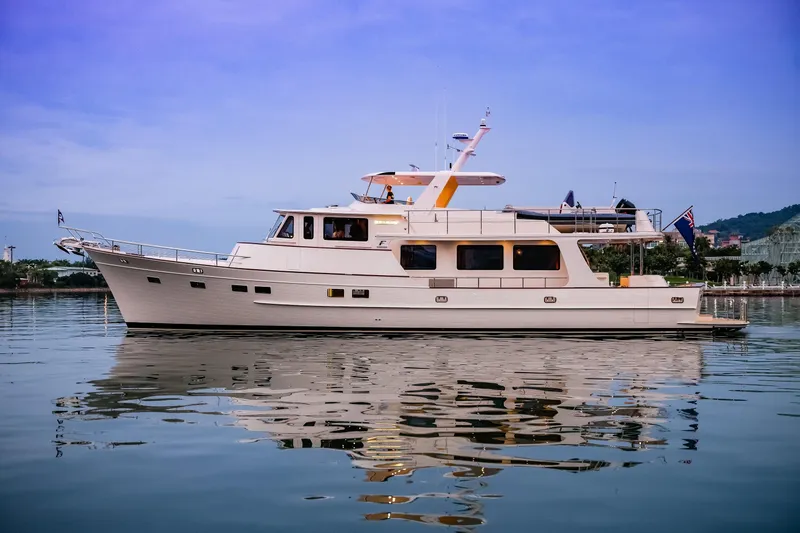 Slide: The Image of 2027 Fleming 85 Pilothouse yacht on calm water, reflecting a serene sky. - 4