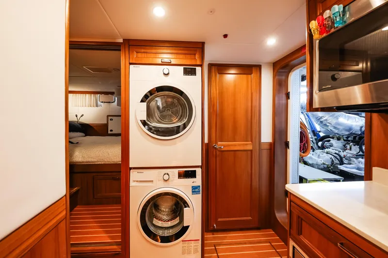 Slide: The Image of Laundry area inside 2027 Fleming 85 Pilothouse yacht, featuring modern appliances and wooden cabinetry. - 93