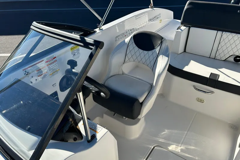 Slide: The Image of 2021 Bayliner DX 2000 boat interior with steering wheel and seating area. - 10