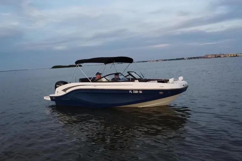 Slide: The Image of 2021 Bayliner DX 2000 boat cruising on calm waters under a cloudy sky. - 19