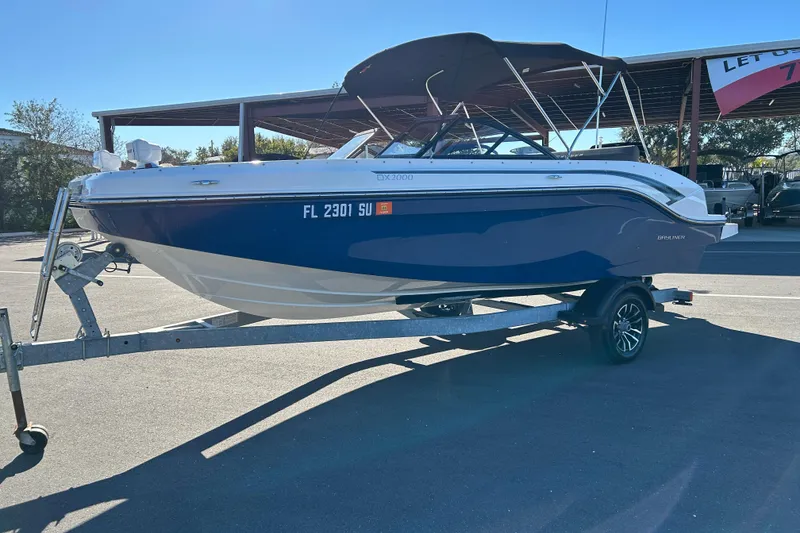 Slide: The Image of 2021 Bayliner DX 2000 boat on trailer, parked outdoors under a canopy. - 5