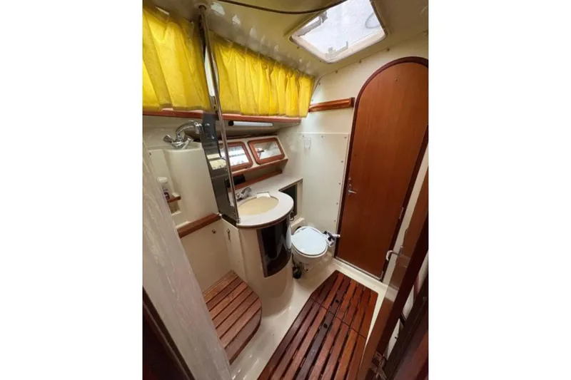 Slide: The Image of 1991 Hunter Legend 37.5 yacht bathroom with wooden accents and yellow curtains. - 15