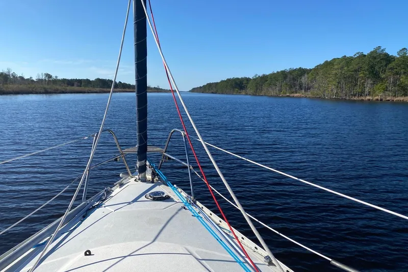 Slide: The Image of Sailing on a 1991 Hunter Legend 37.5 yacht through a serene, tree-lined waterway. - 4