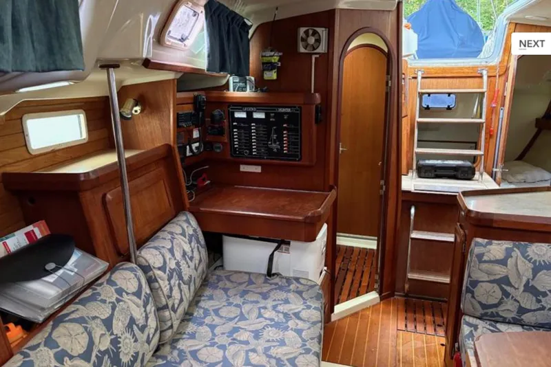 Slide: The Image of Interior of a 1991 Hunter Legend 37.5 sailboat, featuring wood paneling and floral upholstery. - 7