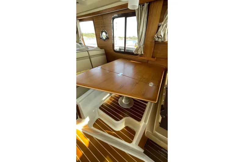 Slide: The Image of Interior of 2025 Ranger Tugs R-31 S with wooden table and striped curtains. - 26