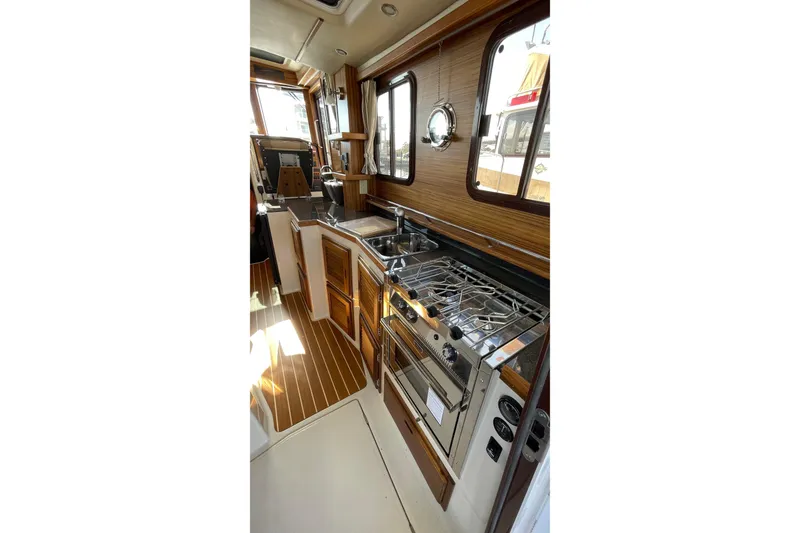 Slide: The Image of 2025 Ranger Tugs R-31 S interior kitchen with wood accents and modern appliances. - 28