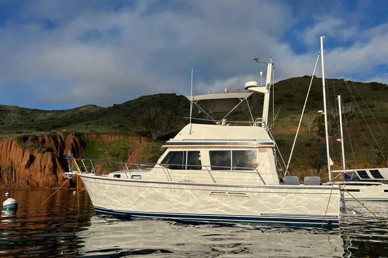 Slide: The Image of 2000 Sabre 34 Flybridge yacht anchored near scenic cliffs and calm waters. - 2