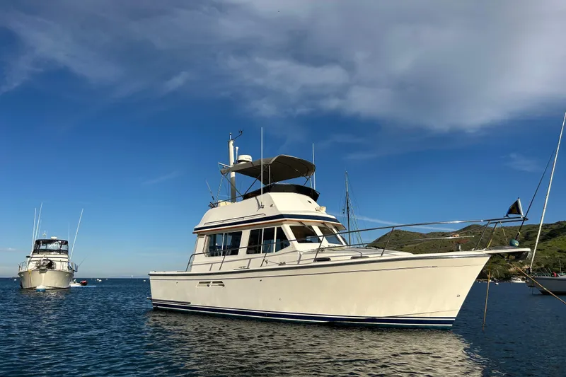 Slide: The Image of 2000 Sabre 34 Flybridge yacht anchored on calm blue waters under a clear sky. - 4