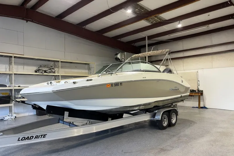 The Image of 2015 NauticStar 223DC Sport Deck boat on trailer in indoor storage. - 0