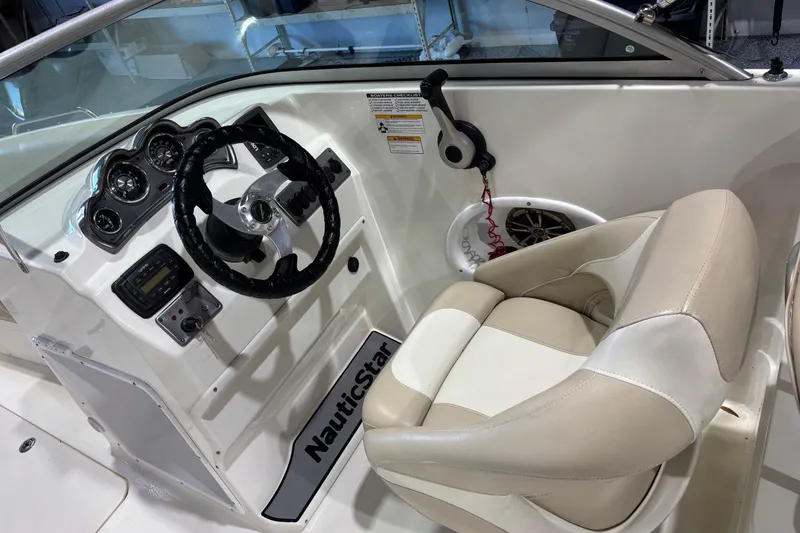Slide: The Image of 2015 NauticStar 223DC Sport Deck boat interior with steering wheel and beige seating. - 7