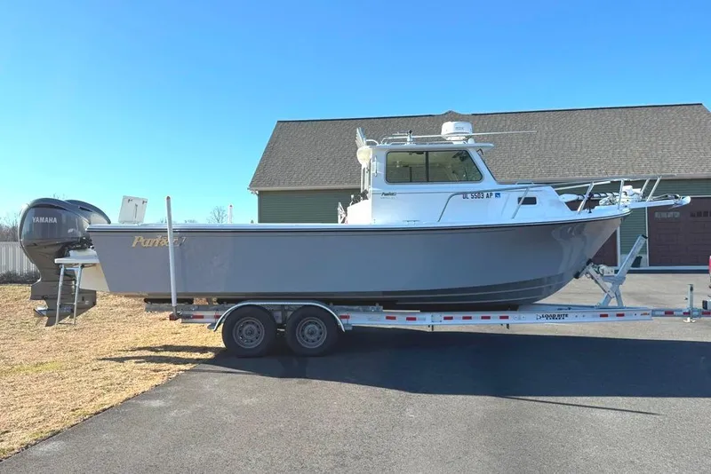 Slide: The Image of 2024 Parker 2820 XLD Sport Cabin boat on trailer, parked outdoors. - 2