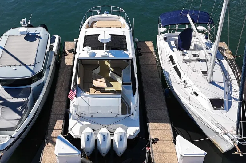 Slide: The Image of 2023 Sea Ray Sundancer 320 Outboard docked between two boats. - 2