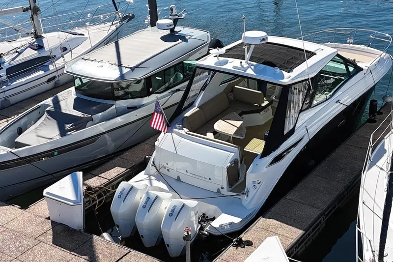 Slide: The Image of 2023 Sea Ray Sundancer 320 Outboard docked, featuring spacious seating and triple outboard engines. - 3