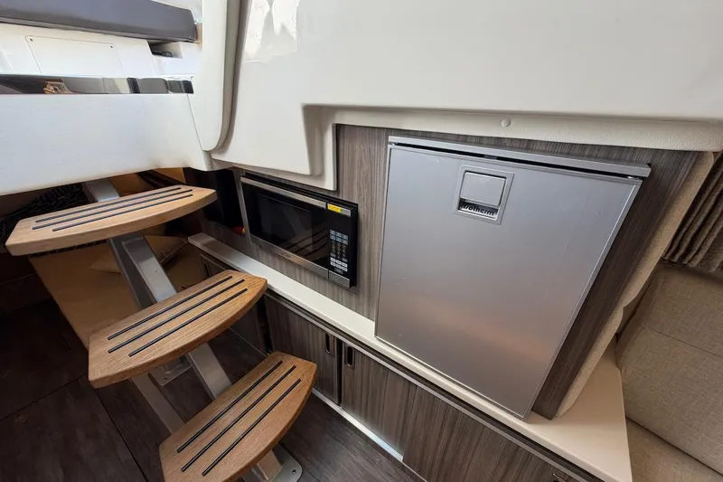 Slide: The Image of 2023 Sea Ray Sundancer 320 Outboard interior with stairs, microwave, and compact fridge. - 33