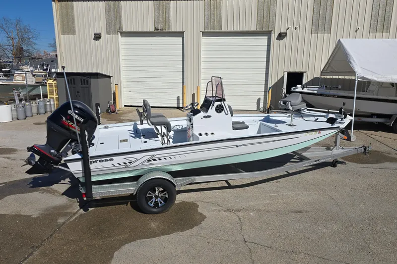 Slide: The Image of 2022 Xpress H20B Bay boat on trailer, parked outside a warehouse. - 7