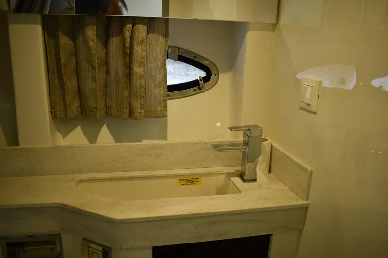Slide: The Image of 2018 Formula 350 Crossover Bowrider OB bathroom sink with modern faucet and porthole window. - 13