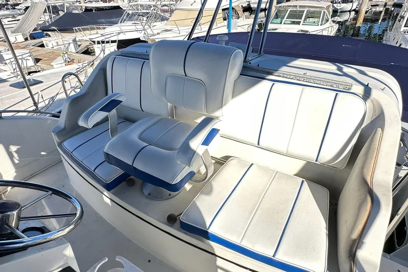 Slide: The Image of 1988 Carver 38 Santego boat seating area with white and blue upholstery at a marina. - 13