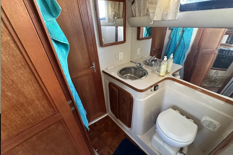 Slide: The Image of 1988 Carver 38 Santego yacht bathroom with sink, toilet, and wooden cabinetry. - 21