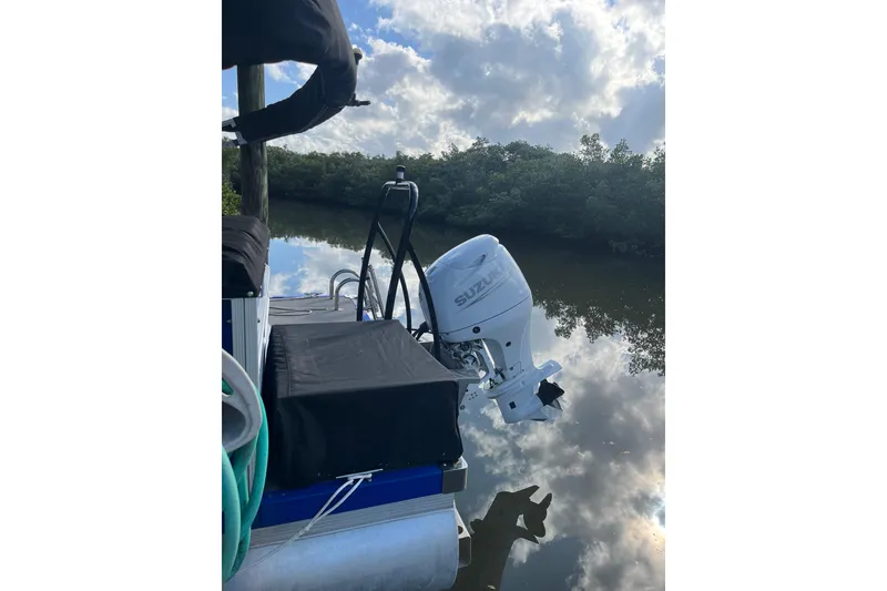 Slide: The Image of 2023 Lexington 321 CRUISE pontoon boat with outboard motor and ladder, parked outdoors. - 3