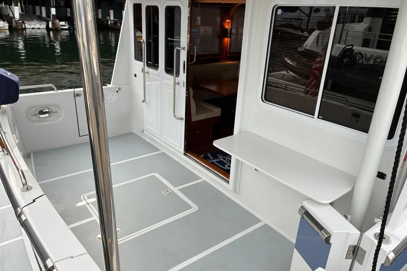 Slide: The Image of 2024 Helmsman Trawlers 43E Pilothouse, spacious deck with seating, docked at marina. - 73