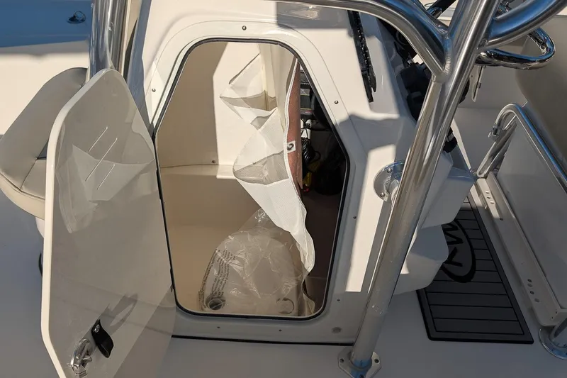 Slide: The Image of 2026 Key West 210 Bay Reef boat console storage area with open door. - 14