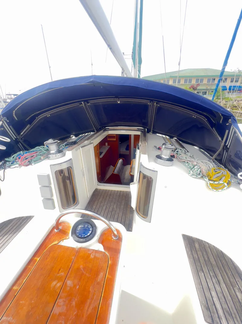 Slide: The Image of 1990 Beneteau 370 sailboat cockpit with open cabin entrance, wooden deck, and nautical equipment. - 11