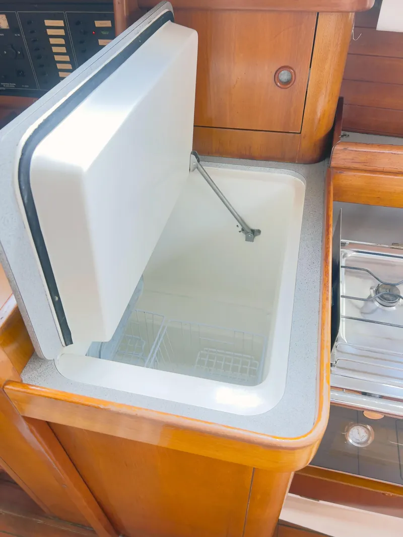 Slide: The Image of Open refrigerator in 1990 Beneteau 370 yacht kitchen, showcasing wooden cabinetry and modern design. - 16