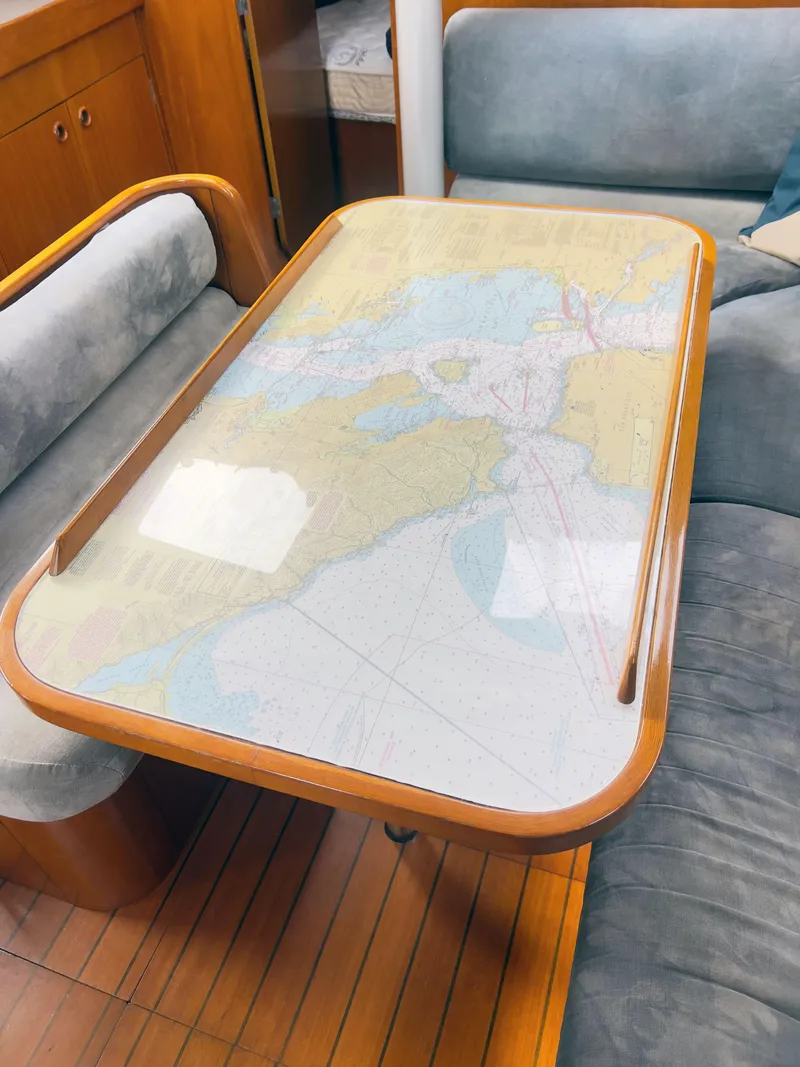 Slide: The Image of Interior of 1990 Beneteau 370 sailboat with nautical chart table and cushioned seating. - 19