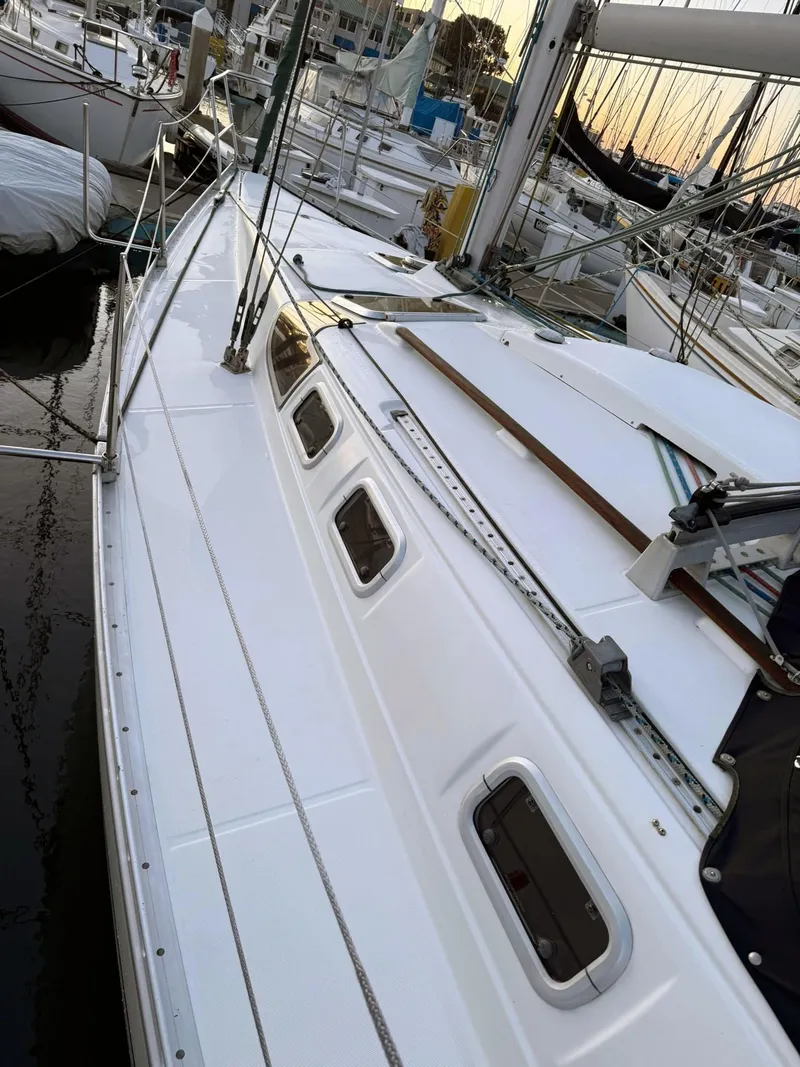 Slide: The Image of 1990 Beneteau 370 sailboat docked, showcasing sleek white deck and rigging. - 5