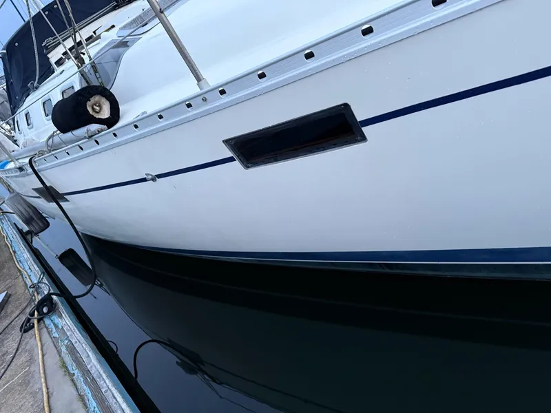 Slide: The Image of 1990 Beneteau 370 sailboat docked, showing sleek white hull and blue stripe. - 7