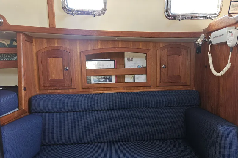Slide: The Image of Interior of 2003 Pacific Seacraft Dana 24 sailboat with wooden cabinetry and blue seating. - 19