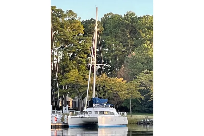 Slide: The Image of 2008 Lagoon 380 S2 catamaran docked by lush green trees. - 2