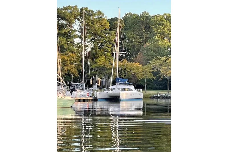 Slide: The Image of 2008 Lagoon 380 S2 catamaran docked by lush trees and calm water. - 3