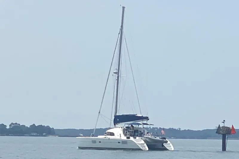 Slide: The Image of 2008 Lagoon 380 S2 catamaran sailing on calm waters near a coastal area. - 5