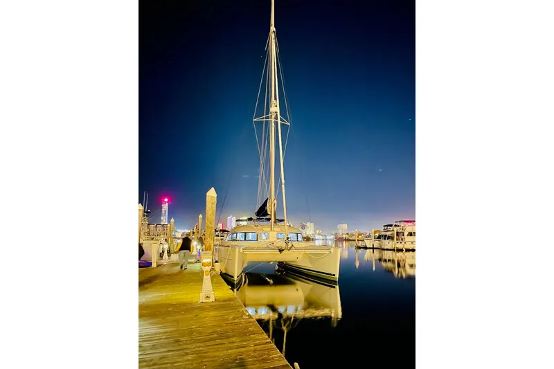 Slide: The Image of 2008 Lagoon 380 S2 catamaran docked at night, reflecting on calm water. - 7