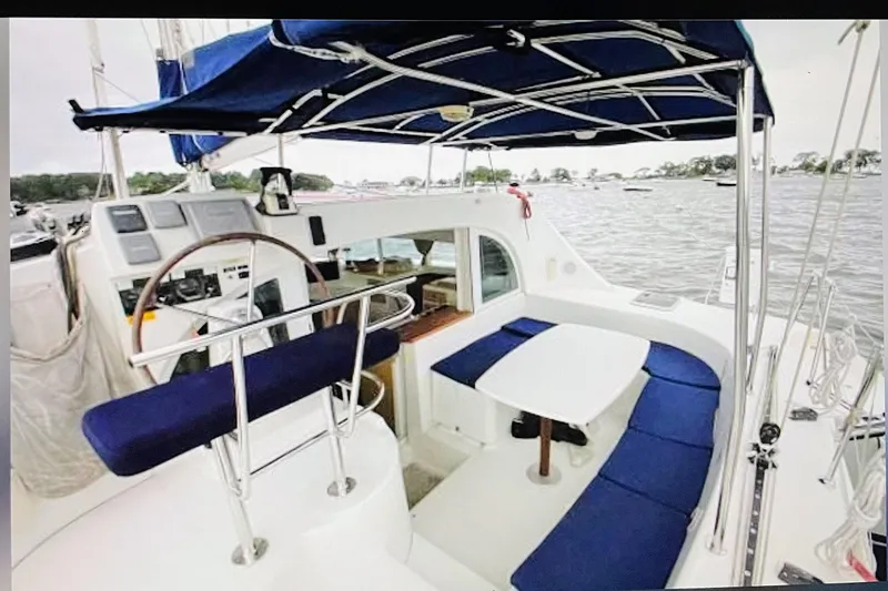 Slide: The Image of 2008 Lagoon 380 S2 catamaran cockpit with blue seating and canopy on the water. - 9