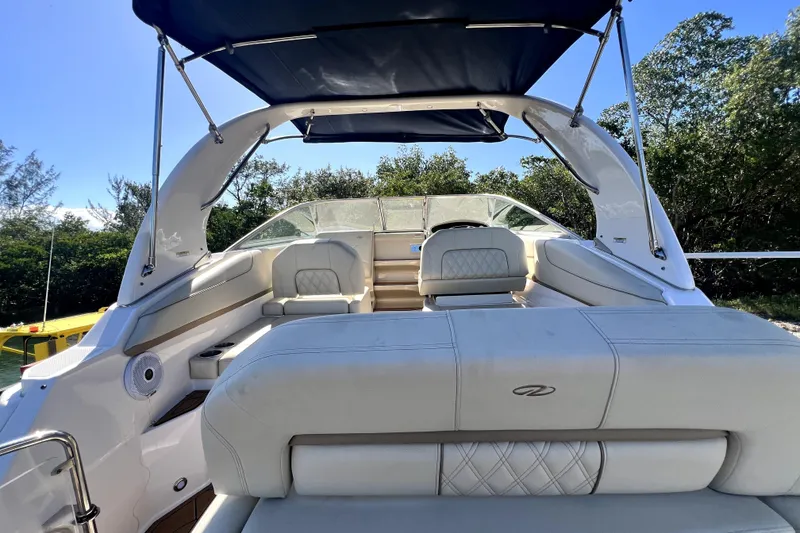 Slide: The Image of 2021 Regal 26 XO boat interior with white seating and canopy, surrounded by greenery. - 21